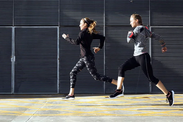 Two beautiful young women running in urban environment. — Stock Photo, Image