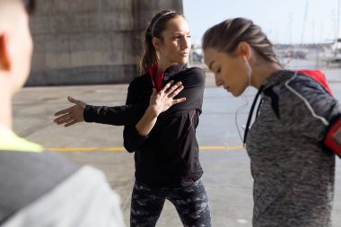 Şehirde germe yapıyor iki formda ve sportif genç kadın.