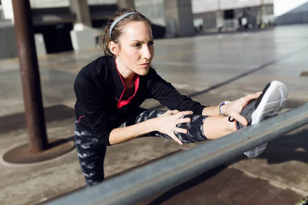 Passform och sportig ung kvinna gör stretching i staden. — Stockfoto