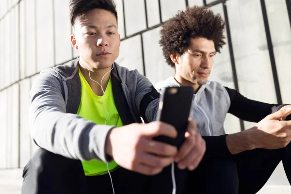 Dos hombres en forma y deportivo youn utilizando el teléfono móvil en la ciudad . —  Fotos de Stock