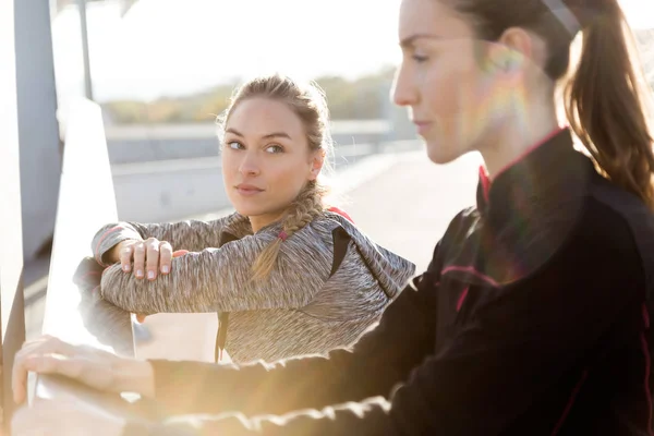 Dos mujeres jóvenes en forma y deportivas haciendo estiramiento en la ciudad . —  Fotos de Stock