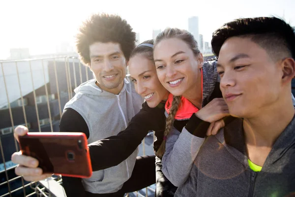 Fit and sporty team using mobile phone in the city. — Stock Photo, Image