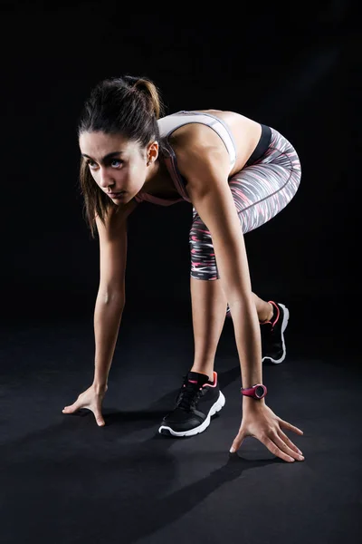 Fit et sportive jeune femme se prépare pour une course sur backgrou noir — Photo