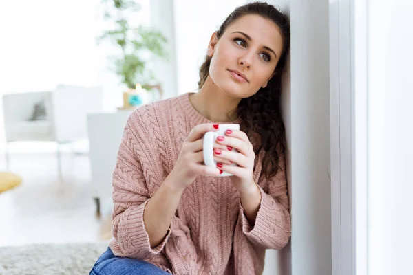 Krásná mladá žena pije kávu doma. — Stock fotografie