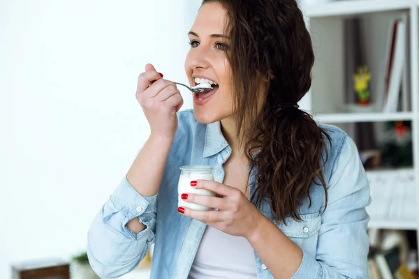 Mooie jonge vrouw eten yoghurt thuis. — Stockfoto