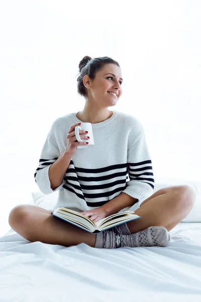 Bella giovane donna che legge un libro sul letto. — Foto Stock