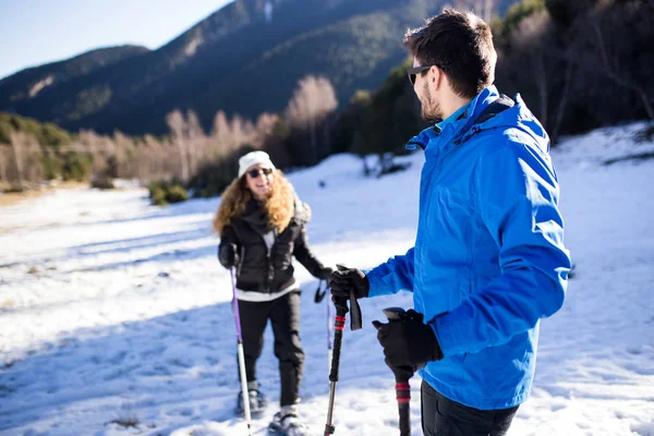 Young couple walking in snowshoes over winter background. — Stock Photo, Image