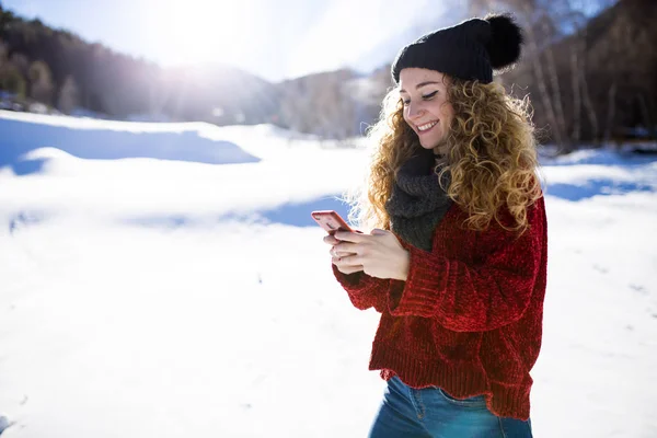 Hermosa mujer joven usando su teléfono móvil durante el invierno backgro — Foto de Stock