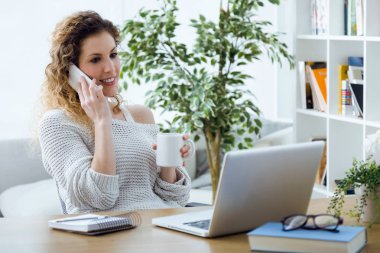 Ofiste cep telefonu kullanan güzel genç kadın.