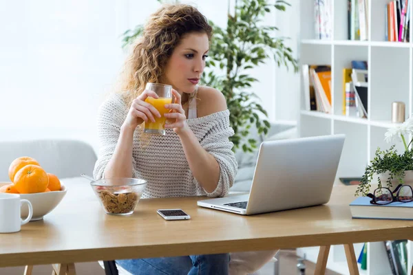 Schöne junge Frau, die zu Hause mit Laptop arbeitet. — Stockfoto