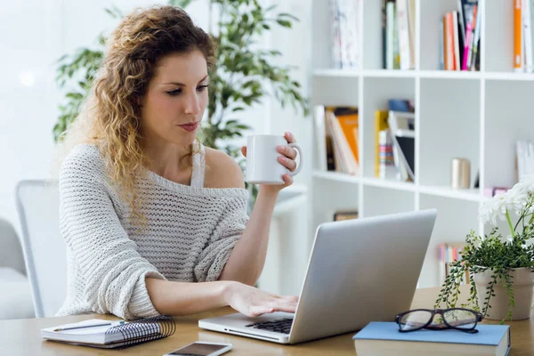 Mooie jonge vrouw met laptop thuis werken. — Stockfoto