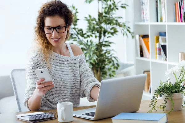 Hermosa mujer joven usando su teléfono móvil en la oficina . — Foto de Stock