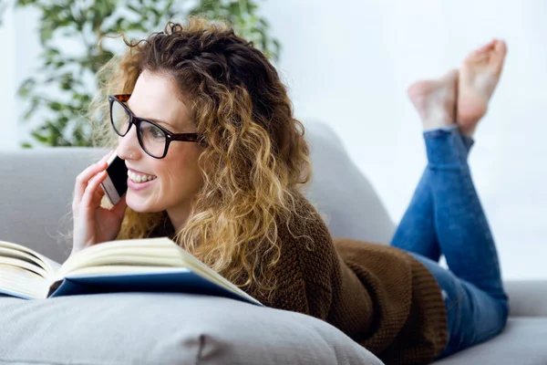 美しい若い女性の家に彼女の携帯電話を使用して. — ストック写真