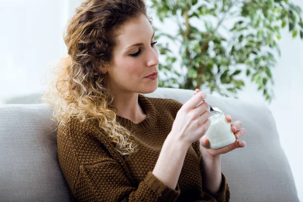 Schöne junge Frau isst Joghurt zu Hause. — Stockfoto