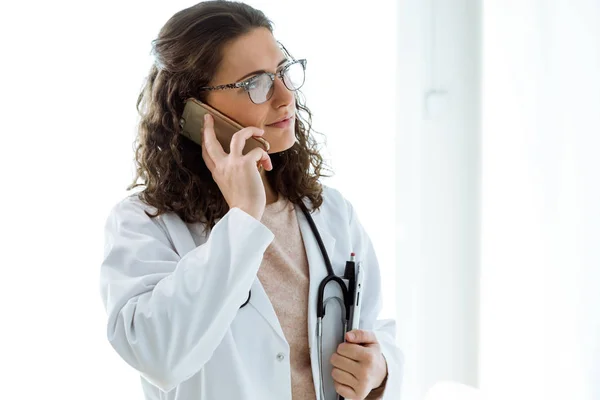 Ženský lékař pomocí svého mobilního telefonu v konzultaci. — Stock fotografie