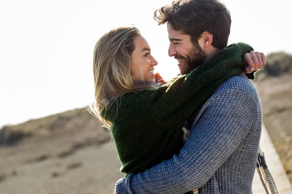 Heureux jeune couple profitant de la journée dans un hiver froid sur la plage . — Photo