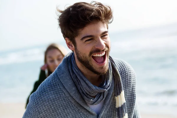 Gelukkige jonge paar genieten van de dag in een koude winter op het strand. — Stockfoto