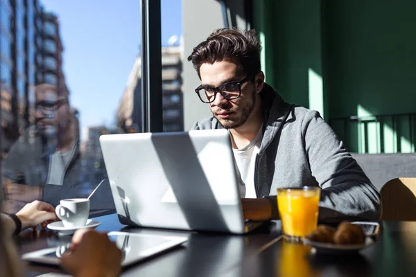 Knappe jonge man met zijn laptop in de koffie. — Stockfoto