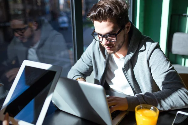 Knappe jonge man met zijn laptop in de koffie. — Stockfoto