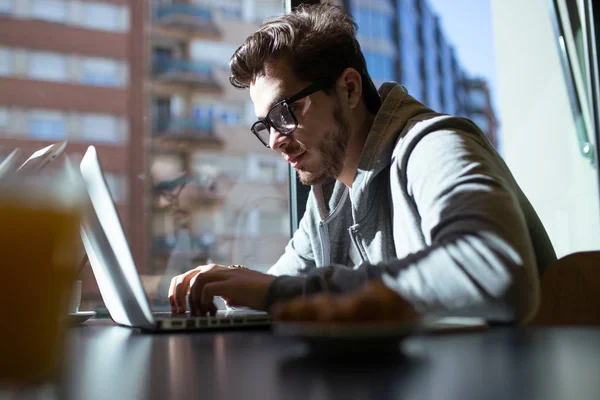 Bello giovane uomo che usa il suo portatile nel caffè . — Foto Stock