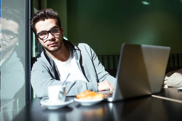 Knappe jonge man met zijn laptop in de koffie. — Stockfoto