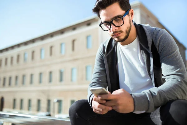 Csinos, fiatal férfi a mobiltelefon használata az utcán. — Stock Fotó