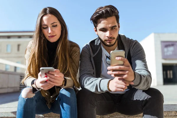 Gyönyörű fiatal pár használ mozgatható telefon-az utcán. — Stock Fotó