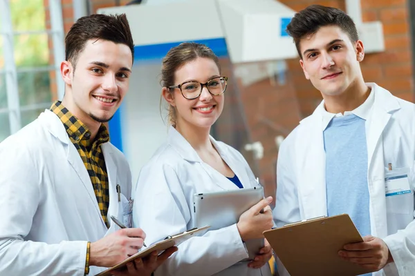 Team di giovani scienziati professionisti che guardano la macchina fotografica in travaglio — Foto Stock