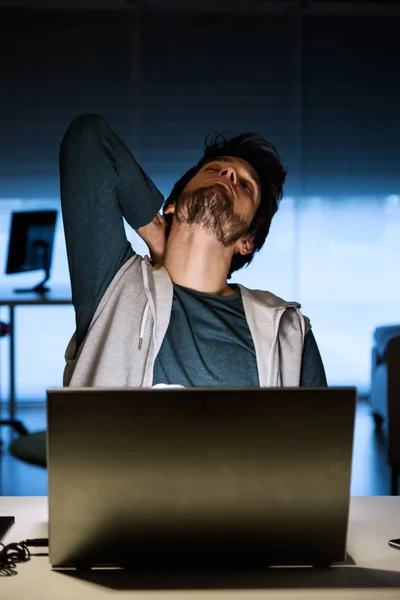 Jovem bonito trabalhando com laptop em seu escritório à noite . — Fotografia de Stock