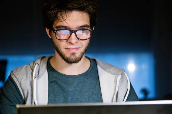 英俊的年轻男子，夜间与笔记本电脑在他的办公室工作. — 图库照片