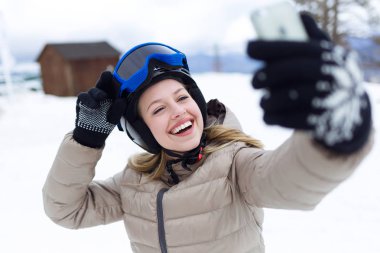 Kış arka plan üzerinde cep telefonu kullanan güzel genç kadın.