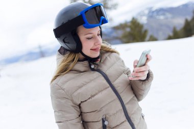 Kış arka plan üzerinde cep telefonu kullanan güzel genç kadın.