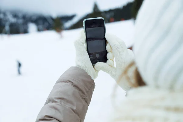 Schöne junge Frau mit ihrem Handy über Winter Hintergrund. — Stockfoto