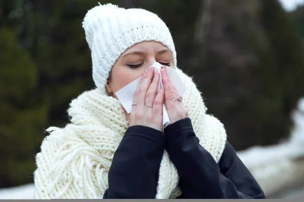 Όμορφη νεαρή γυναίκα με ιστό έχοντας γρίπη πέρα από το υπόβαθρο του χειμώνα. — Φωτογραφία Αρχείου