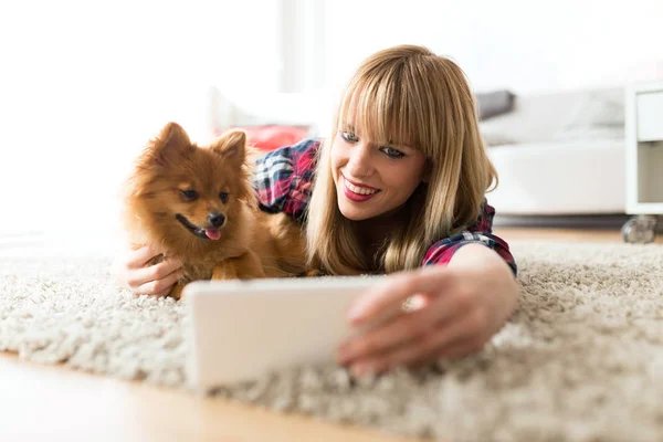 Mulher bonita com seu cão usando telefone celular em casa . — Fotografia de Stock