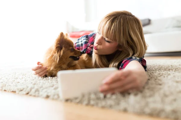 Mulher bonita com seu cão usando telefone celular em casa . — Fotografia de Stock