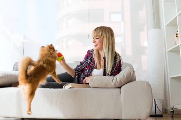 Belle jeune femme avec son chien jouant avec la balle à la maison . — Photo