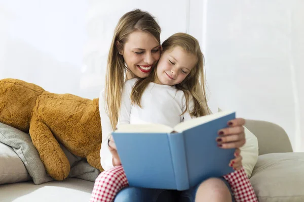 Piękne matki z córką, czytanie książki w domu. — Zdjęcie stockowe