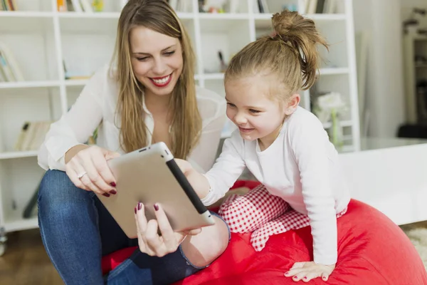 Krásná matka a dcera hraje s digitálním tabletu doma. — Stock fotografie