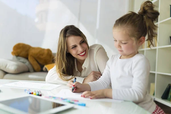 Beautiful mother with her daughter drawing with crayons at home. — Stock Photo, Image