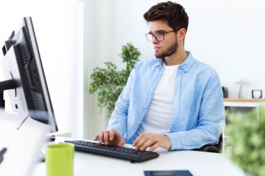 Yakışıklı genç adam modern ofis içinde laptop ile çalışma.