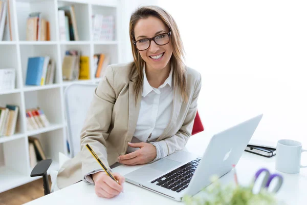 Vacker ung kvinna som arbetar med laptop-kontoret. — Stockfoto