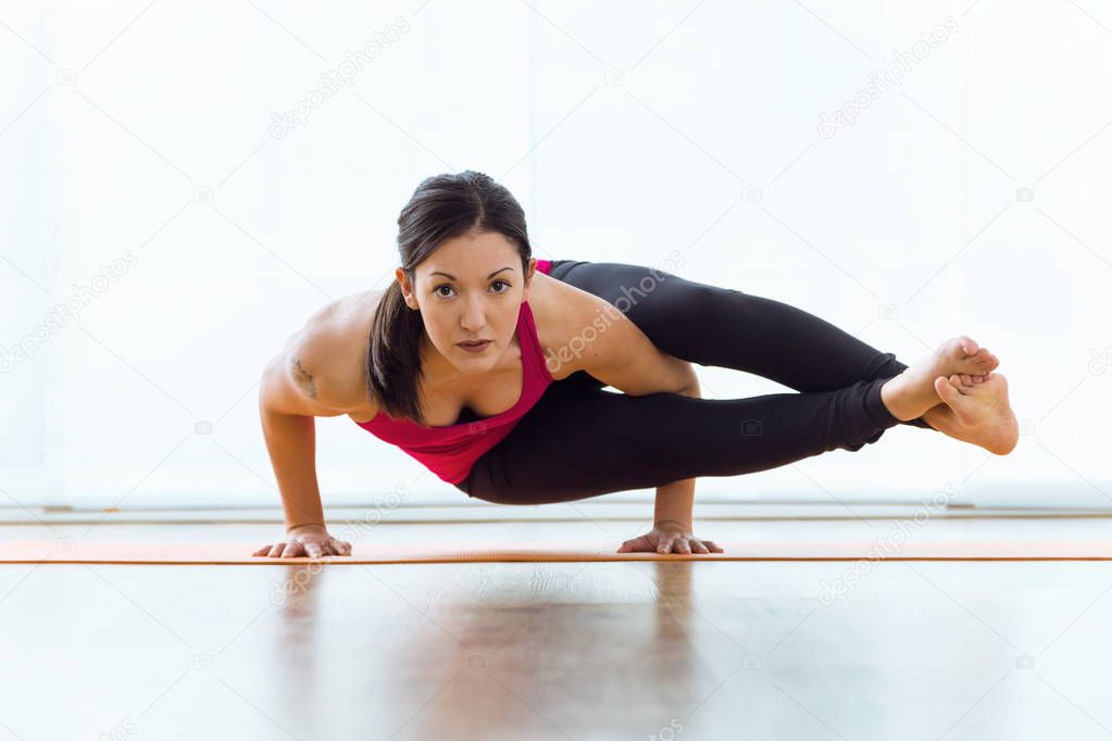 Beautiful young woman practicing yoga at home.