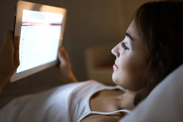 Mulher bonita usando seu tablet digital na cama no nig — Fotografia de Stock