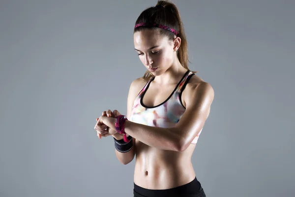 Подтянутая и спортивная молодая женщина смотрит свои часы на белом фоне — стоковое фото