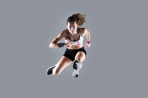 Ajuste y deportivo joven mujer saltando sobre fondo blanco . — Foto de Stock