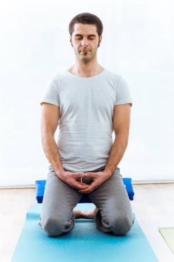 Evde yoga pratik güzel genç adam. Vajrasana poz.