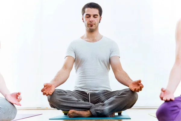 Jovem bonito praticando ioga em casa. pose de Sukhasana . — Fotografia de Stock