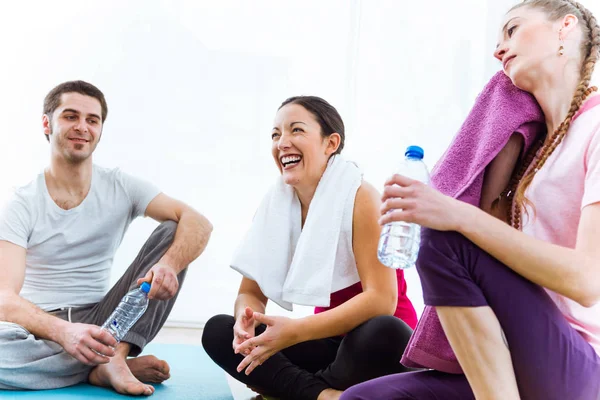 Gruppo di persone che si rilassano sul tappetino yoga e parlano dopo la sessione di allenamento . — Foto Stock