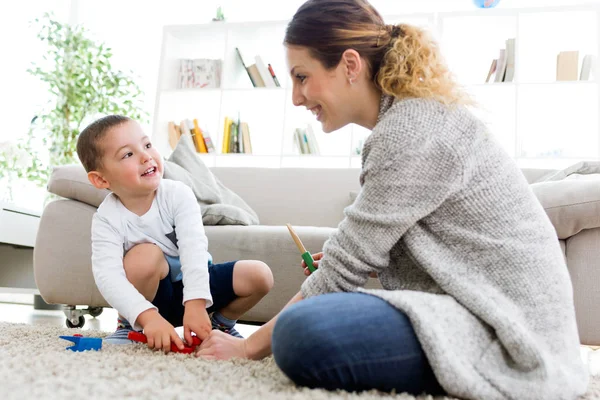 Bela jovem mãe e seu filho se divertindo em casa . — Fotografia de Stock